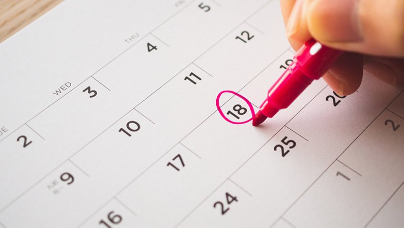 Women circling first day she can take a pregnancy test on a calendar with pink marker.