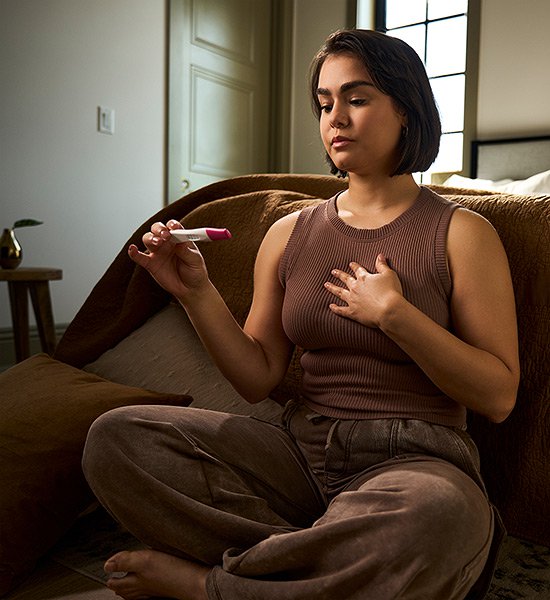 Woman holding a First Response pregnancy test stick.