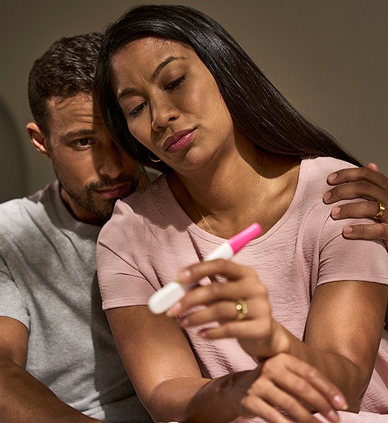 TTC couple looking at a First Response pregnancy test waiting for results.