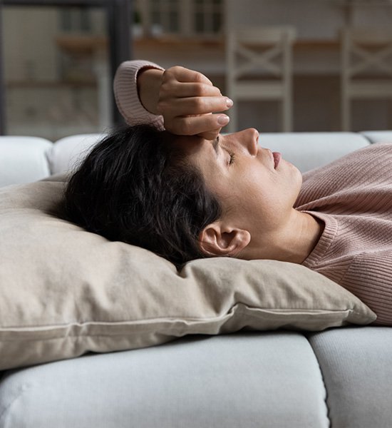 Woman laying down and resting on couch.